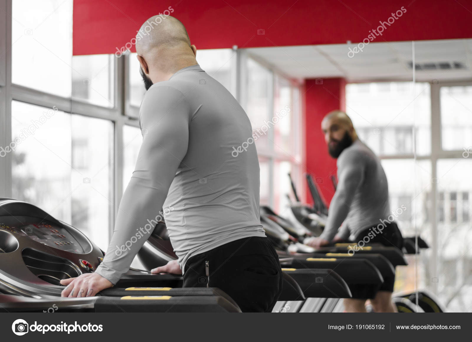 Man training on treadmill looking at his reflection in mirror
