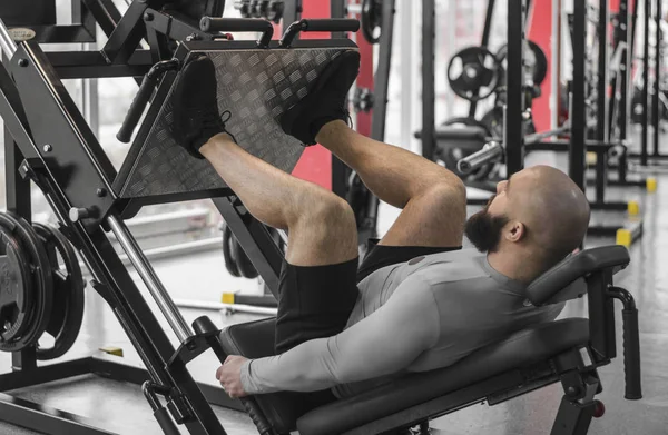 Güçlü adam fit kaslı vücut egzersizleri bacak basın makinede yapıyor ile egzersiz — Stok fotoğraf