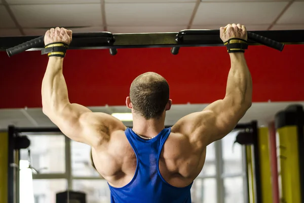 Bodybuilder musculaire avec corps fort faisant des exercices de menton-up, formation à la salle de gym — Photo