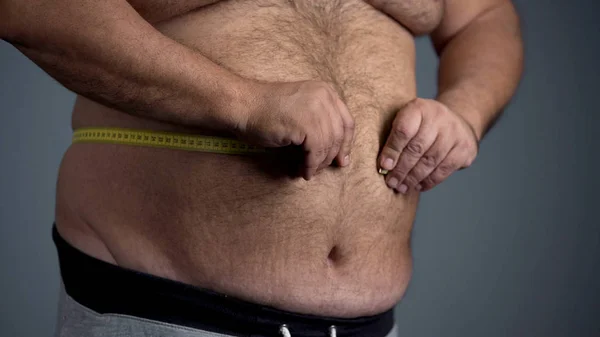 Triste hombre con sobrepeso incapaz de medir su cintura, barriga gorda con estrías — Foto de Stock