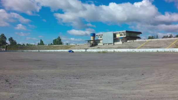 Mobil mengemudi di lingkaran balap di ditinggalkan autodrome dengan latar langit biru — Stok Video