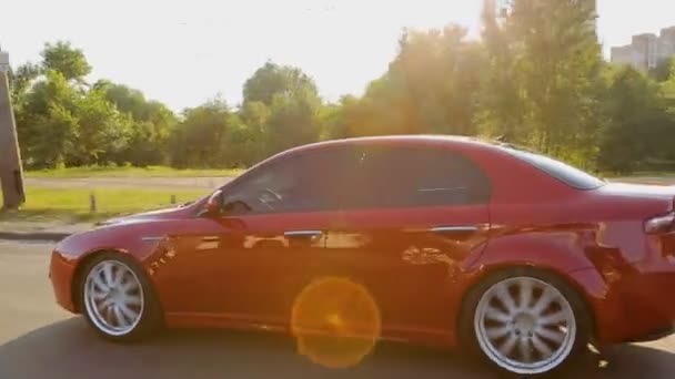 Rosso auto di lusso in movimento strada cittadina lungo il parco verde, ricreazione ad alta velocità, viaggio — Video Stock