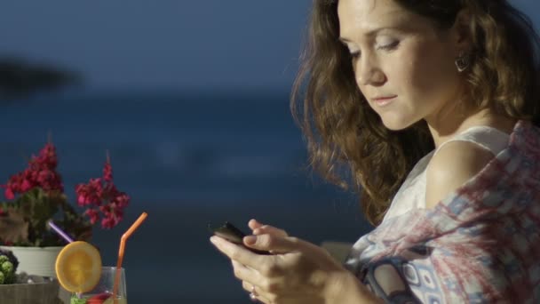 Feliz hermosa mujer charlando en línea en el teléfono inteligente en el restaurante al aire libre — Vídeos de Stock