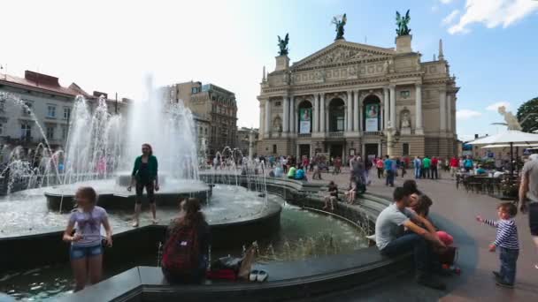 Lvov, Ukrajina - cca červenec 2017: Lidé ve městě. Turisté relaxační fontána, pěkný pohled Lvovskému divadlu opery a baletu — Stock video