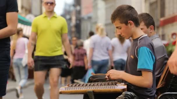 LVIV, UCRANIA - CIRCA JULIO 2017: Personas en la ciudad. Adolescentes tocando música dulcimer en la avenida llena de gente, músicos callejeros, hobby — Vídeos de Stock