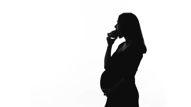 Silhouette of pregnant woman eating apple, healthy diet during childbearing — Stock Video