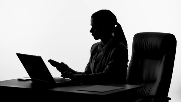 Женщина-босс работает над своим ноутбуком, отвечает на телефонный звонок, инсайдерская информация — стоковое видео