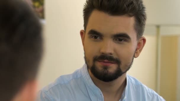 Sonriente hombre peinándose el pelo mirando el reflejo en el espejo, teniendo una cita — Vídeos de Stock