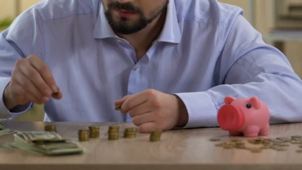 Solteiro escrúpulo planejando seu orçamento mensal, colocando moeda no mealheiro — Vídeo de Stock