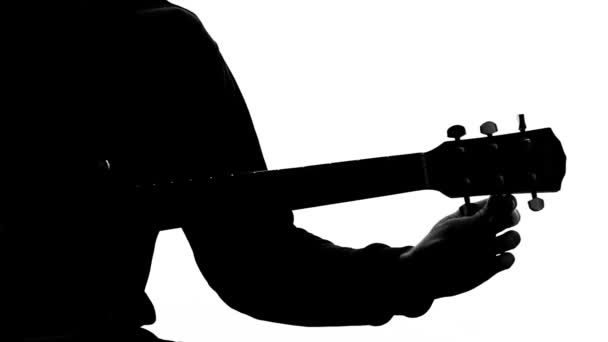 Силуэт мужского музыканта, настраивающего акустическую гитару, молодого композитора, хобби — стоковое видео