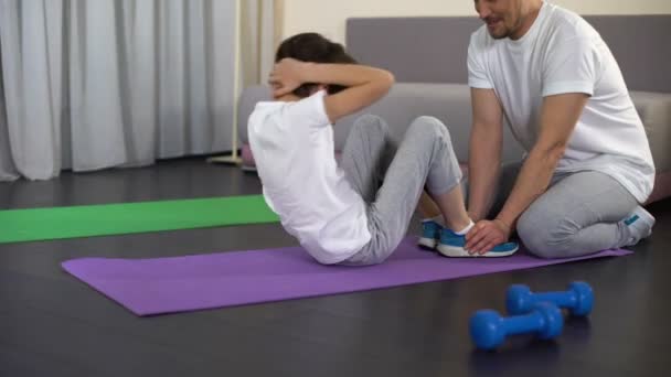 Pequeño niño haciendo abdominales y dando choca a su padre, haciendo ejercicio en casa — Vídeo de stock