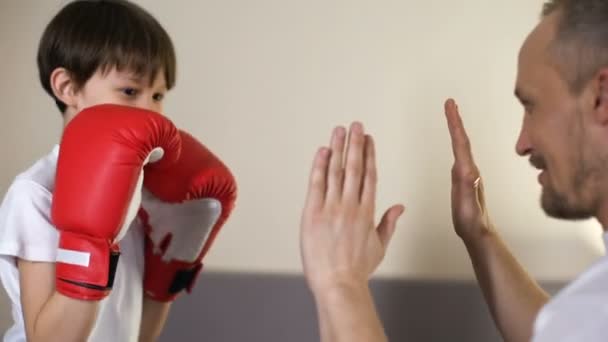 Enfant mignon pratiquant des coups de boxe avec son entraîneur, s'amusant avec son père, le sport — Video