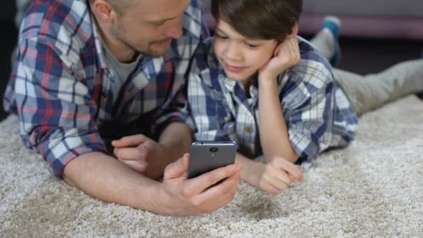 Pai mostrando filho aplicativo engraçado no smartphone, passar tempo juntos — Vídeo de Stock