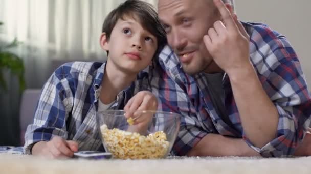 Vader van knuffelen zoontje tijdens kijken film huis met popcorn, trots van kind — Stockvideo