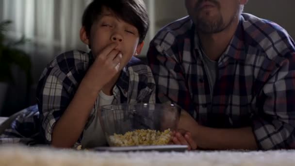 Stepfather and son watching TV at home until late and eat junk food, closeness — Stock Video