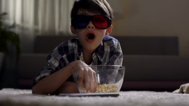 Piccolo ragazzo che guarda film in bicchieri 3d e mangia popcorn, godendo a casa — Video Stock