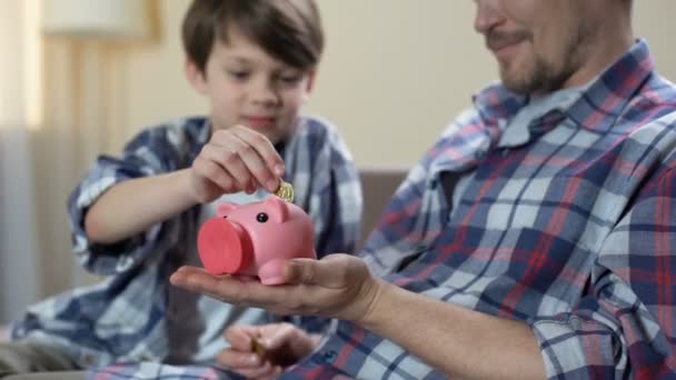 Vader en zoon munt ingebruikneming piggy bank en het geven van hoge vijf, opslaan voor droom — Stockvideo