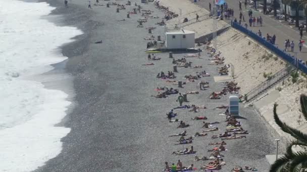 Nice, FRANCE - CIRCA JUNE 2016: People on the beach. Туристы, лежащие на солнечном пляже в Ницце, французский курортный город, летний отдых — стоковое видео
