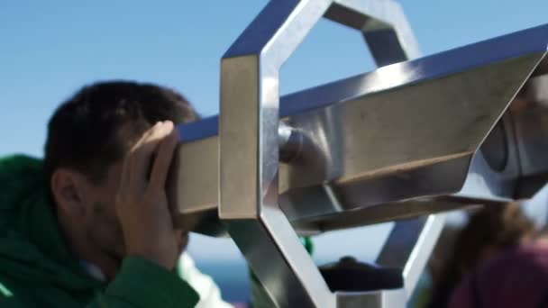 Male tourist looking at cityscape through binoculars at sightseeing platform — Stock Video