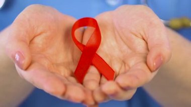 Kadın doktor holding kırmızı kurdele, bakım ve HIV pozitif çocukların korunması
