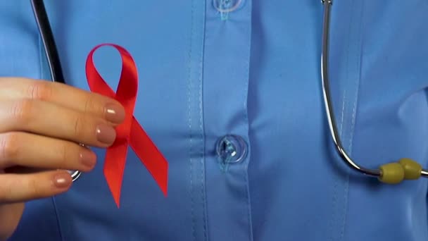 Γυναίκα Γιατρό Κρατώντας Κόκκινη Κορδέλα Και Προφυλακτικό Στα Χέρια Της — Αρχείο Βίντεο