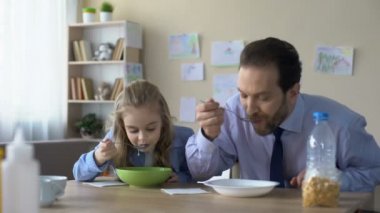 Mutlu küçük kız ve baba kahvaltıda, Aile geleneklerine Mısır gevreği yemek