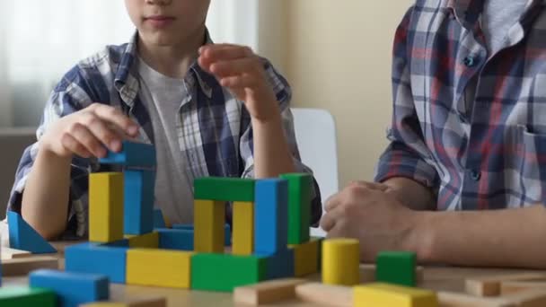 Intelectualmente discapacitado adolescente jugando con cubos, voluntario cuidar de él — Vídeos de Stock