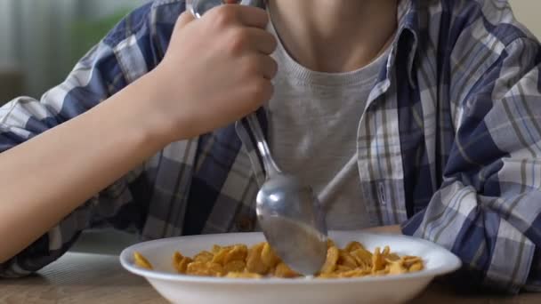 Junge mischt widerwillig Cornflakes mit Löffel, verärgertes Kind, Appetitlosigkeit — Stockvideo