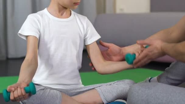 Chłopiec siedzi i zniesienie dumbbells trener wsparcie, pomoc ojca, fitness — Wideo stockowe