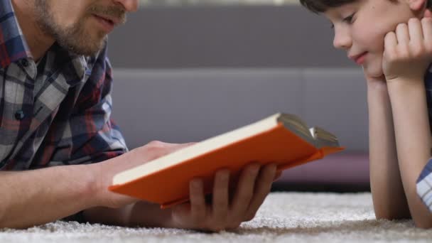 Vater liest Sohn Märchen auf dem Boden liegend vor, Freizeit im Vorschulalter — Stockvideo