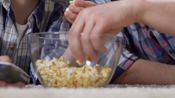 男性手在看电视、不健康食物时从玻璃碗里拿爆米花 — 图库视频影像