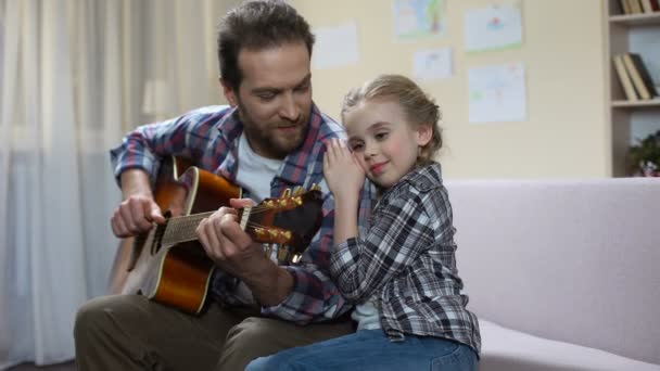 Filha abraçando e ouvindo o pai tocando guitarra, tempo livre juntos — Vídeo de Stock