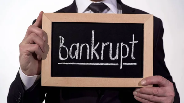 Bankrupt written on blackboard in businessman hands, loss of money and property — Stock Photo, Image