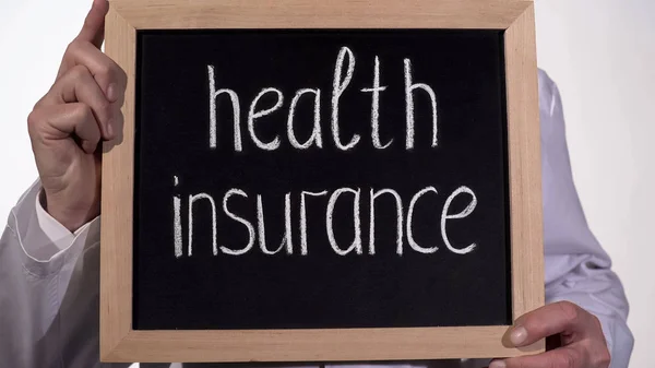 Ubezpieczenie zdrowotne tekst na tablicy w ręce lekarza, drogich medycyny rodzinnej — Zdjęcie stockowe
