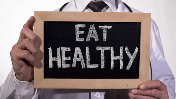 Eat healthy diet recommendation written on blackboard in nutrition doctor hands