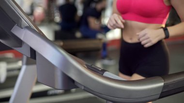 Düz mide ve ince kalça aktif genç kadının spor salonunda treadmill yürüyüş