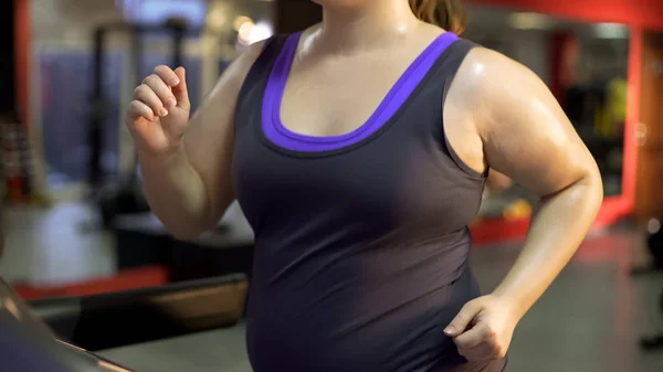 Сильная женщина с избыточным весом, упорно работающая, чтобы похудеть, потеющая на беговой дорожке — стоковое фото