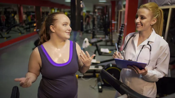 Emocionado entrenamiento de la mujer en el gimnasio, hablando con el nutricionista, motivado por los resultados —  Fotos de Stock