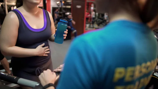 Mujer embarazada consultando con entrenador personal sobre ejercicios de embarazo en el gimnasio —  Fotos de Stock