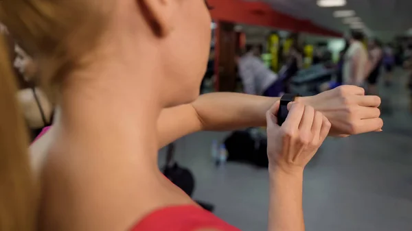 Sportliche Frau wechselt Fitness-Tracker-Armband vor aktivem Training im Fitnessstudio — Stockfoto