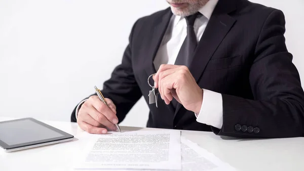 Агент з нерухомості тримає ключі від будинку для клієнта та підписує іпотечні документи — стокове фото