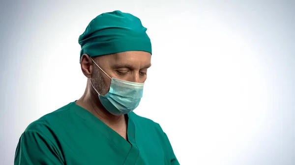 Cirujano masculino reflexivo se puso la mascarilla antes de la operación seria, concentrado — Foto de Stock