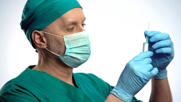 Врач в маске держит шприц, готовится сделать инъекцию, вакцину от гриппа — стоковое фото