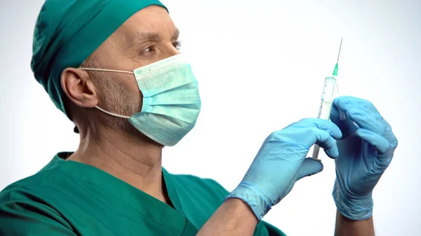 Доктор в маске, получающий пузырьки воздуха из шприца перед вакциной — стоковое фото