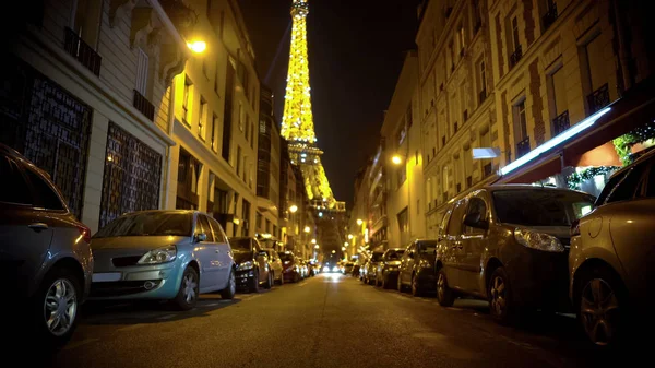 Tour Eiffel étincelante en arrière-plan, voitures garées des deux côtés de la rue étroite — Photo