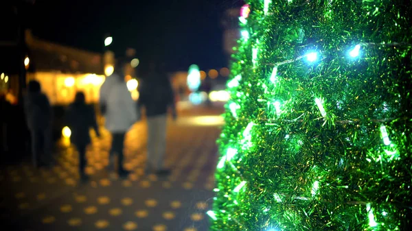 Noel ağacı, arka plan üzerinde geziniyor çocuklu aile üzerinde parlak ışıklar — Stok fotoğraf