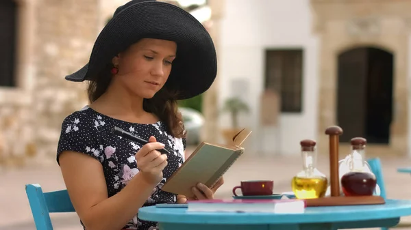 Hermosa joven leyendo interesante libro, marcando lugares favoritos con pluma —  Fotos de Stock