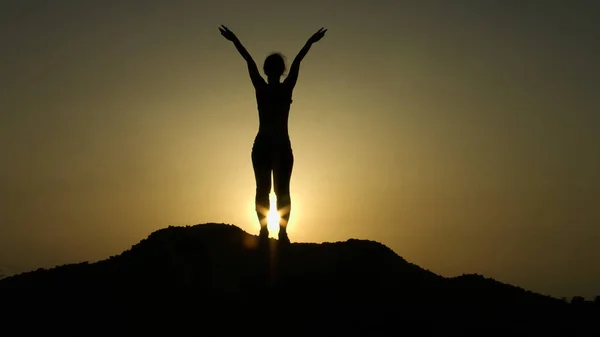 Νεαρή γυναίκα κάνει διατάσεις ασκήσεις πρωί στην κορυφή βουνού — Φωτογραφία Αρχείου