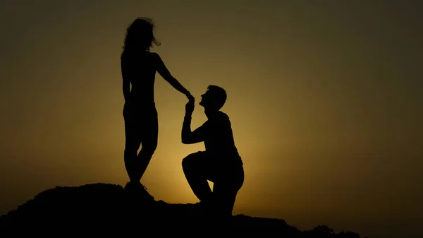 Sylwetka młody człowiek proponuje dziewczynie na kolanie, romantyczne zaręczyny — Zdjęcie stockowe
