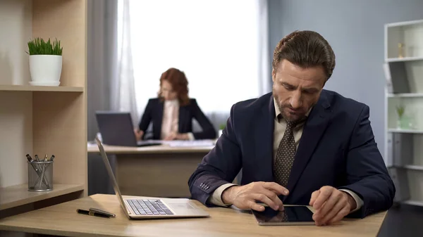 Bedrijf werknemer typen op laptop, zoeken naar informatie op tablet, analyse — Stockfoto